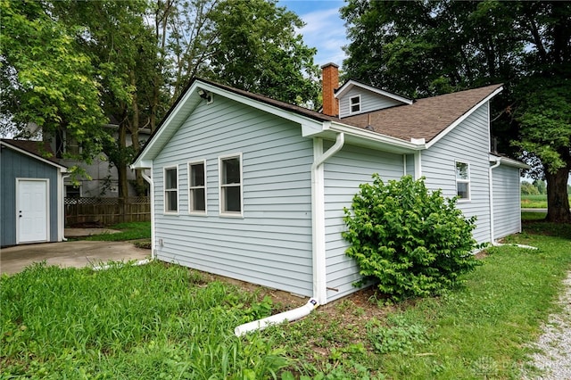 view of home's exterior with a shingled roof, a patio, fence, and a chimney