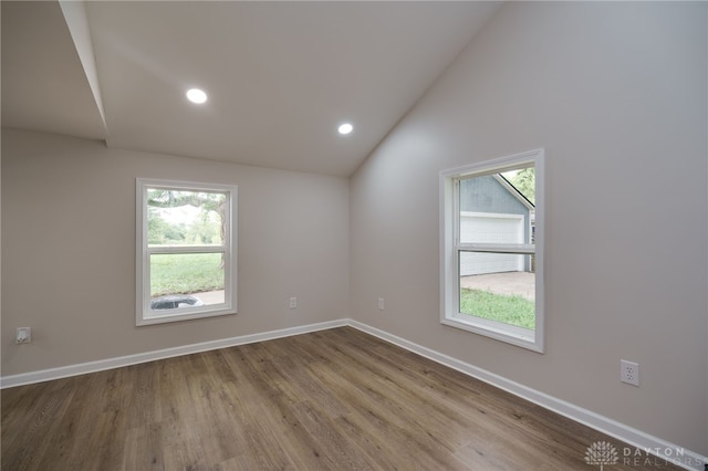 spare room featuring recessed lighting, baseboards, wood finished floors, and vaulted ceiling