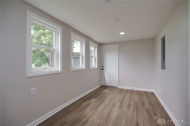 spare room featuring recessed lighting, electric panel, wood finished floors, and baseboards