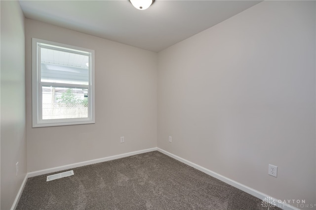 empty room with visible vents, baseboards, and dark colored carpet