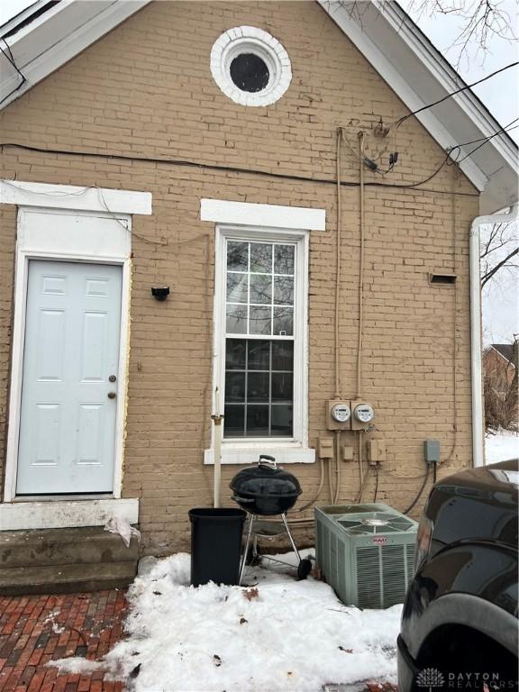 snow covered property entrance featuring central AC