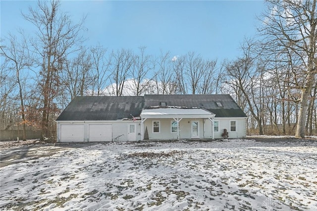 snow covered rear of property featuring a garage and a porch