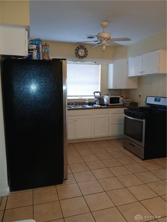 kitchen with light tile patterned flooring, sink, white cabinets, ceiling fan, and stainless steel appliances