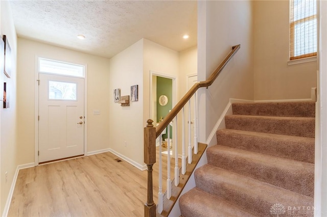 foyer entrance with hardwood / wood-style floors and a textured ceiling