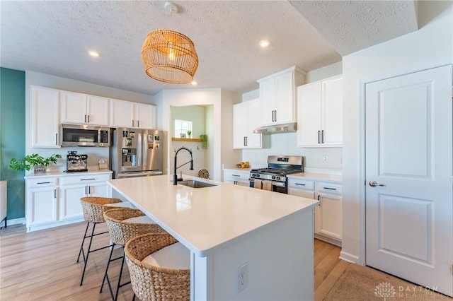 kitchen featuring a kitchen island with sink, sink, stainless steel appliances, and white cabinets