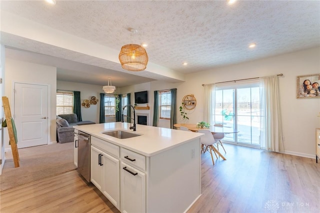 kitchen featuring sink, a textured ceiling, stainless steel dishwasher, and white cabinets