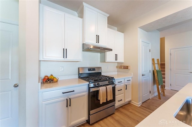 kitchen with gas range, light hardwood / wood-style floors, and white cabinets