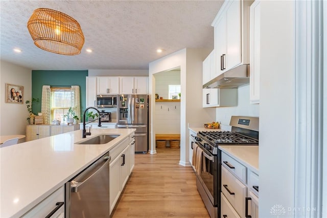 kitchen with pendant lighting, sink, stainless steel appliances, and white cabinets