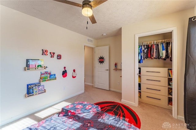 bedroom with light carpet, a textured ceiling, ceiling fan, and a closet