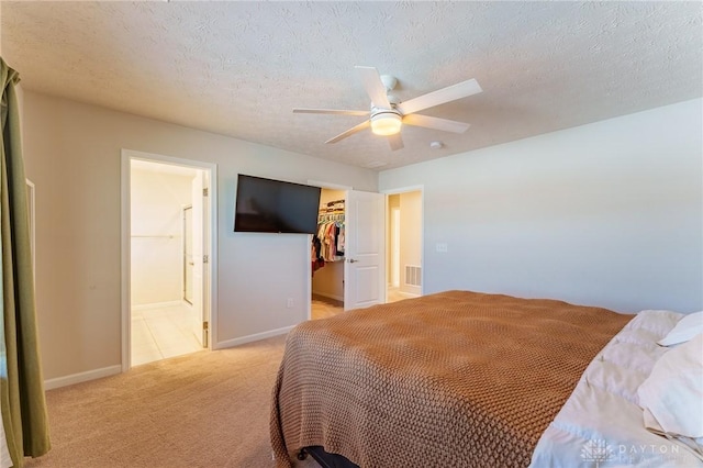 bedroom with a spacious closet, ceiling fan, light carpet, a textured ceiling, and a closet