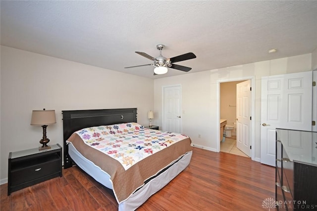 bedroom featuring ensuite bath, a textured ceiling, ceiling fan, and hardwood / wood-style flooring