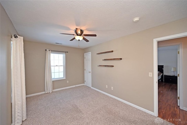 unfurnished room with ceiling fan, carpet flooring, and a textured ceiling