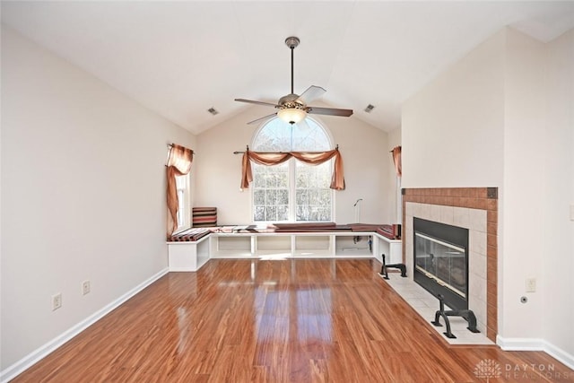 interior space featuring light hardwood / wood-style flooring, vaulted ceiling, a tile fireplace, and ceiling fan