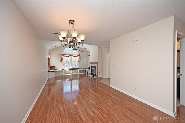 unfurnished dining area featuring lofted ceiling, hardwood / wood-style floors, and ceiling fan with notable chandelier