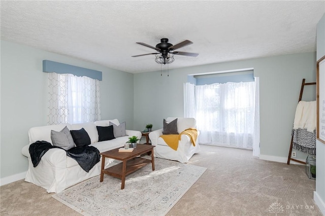 carpeted living room featuring ceiling fan and a textured ceiling