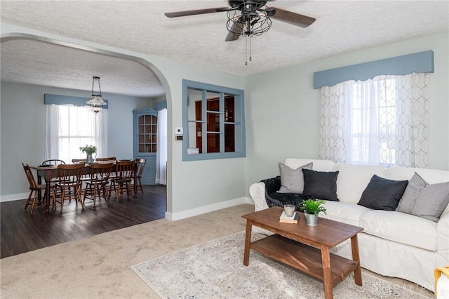 carpeted living room with ceiling fan and a textured ceiling