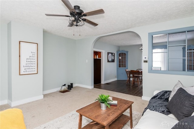 living room featuring ceiling fan, carpet floors, and a textured ceiling