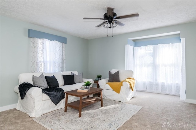 living room featuring light carpet, ceiling fan, and a textured ceiling