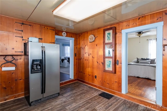 kitchen featuring wooden walls, dark hardwood / wood-style floors, and stainless steel refrigerator with ice dispenser