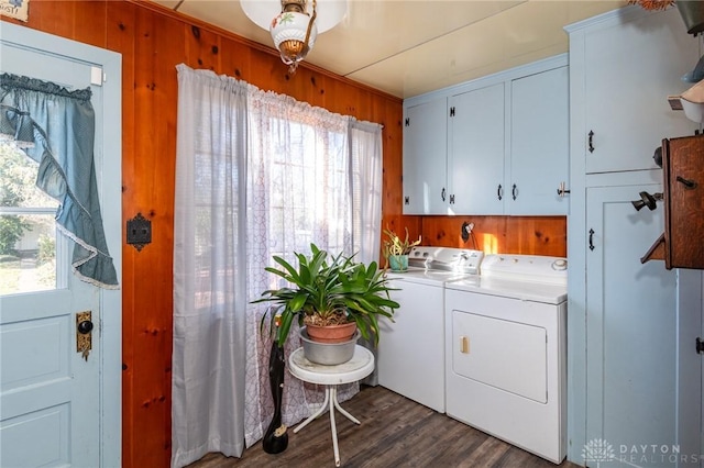 clothes washing area with cabinets, separate washer and dryer, dark hardwood / wood-style flooring, and wood walls