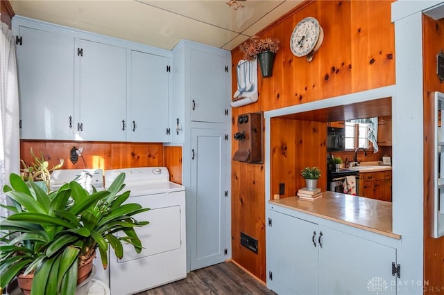 laundry area with sink, cabinets, dark hardwood / wood-style floors, washer / dryer, and wood walls