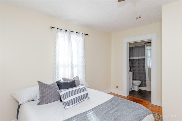 bedroom with ensuite bath, a textured ceiling, and hardwood / wood-style flooring