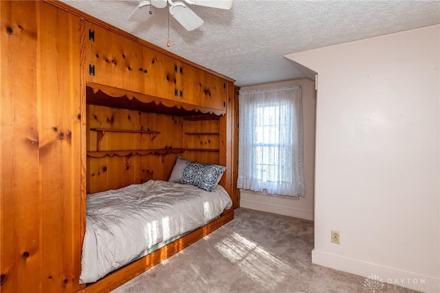 bedroom featuring ceiling fan, light colored carpet, and a textured ceiling