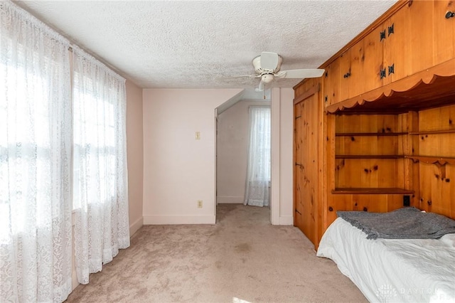 bedroom with a textured ceiling, light colored carpet, and ceiling fan