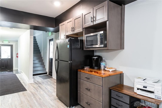 kitchen with black refrigerator, wooden counters, and light hardwood / wood-style floors