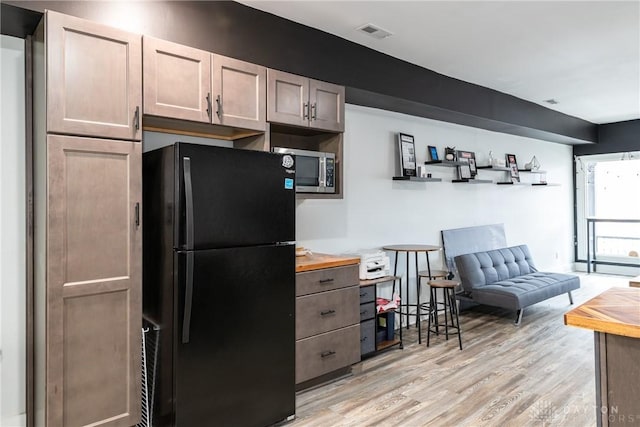 kitchen featuring black refrigerator, light hardwood / wood-style floors, and wooden counters