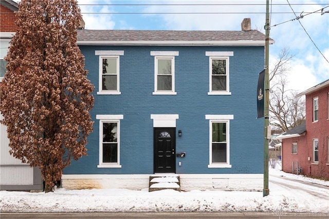 colonial home featuring brick siding and a chimney