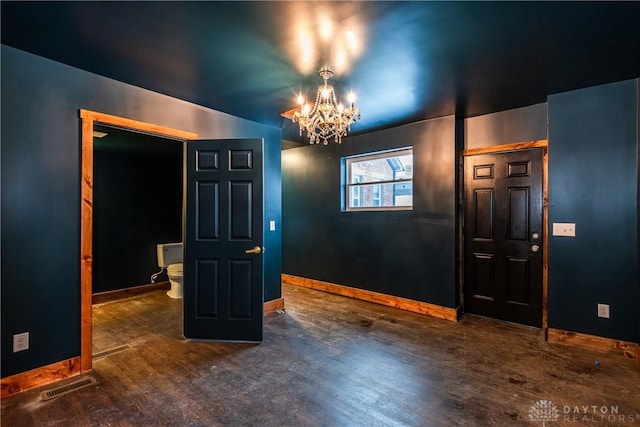 spare room with dark hardwood / wood-style floors and a notable chandelier