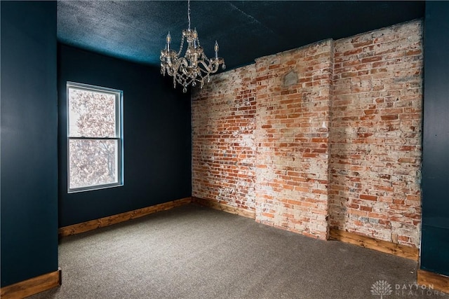 carpeted spare room with brick wall, a notable chandelier, and a textured ceiling