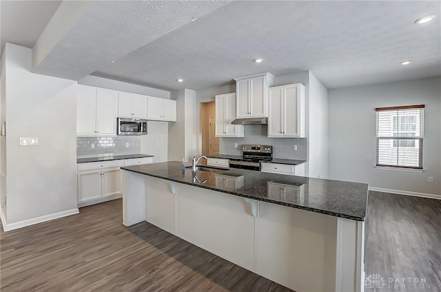 kitchen featuring sink, a breakfast bar area, appliances with stainless steel finishes, dark stone countertops, and white cabinets