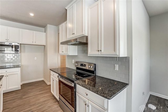 kitchen with backsplash, stainless steel appliances, dark stone countertops, and white cabinets