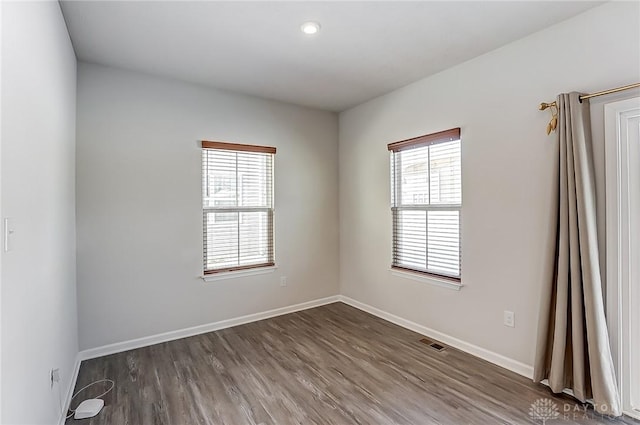 empty room featuring plenty of natural light and dark hardwood / wood-style floors