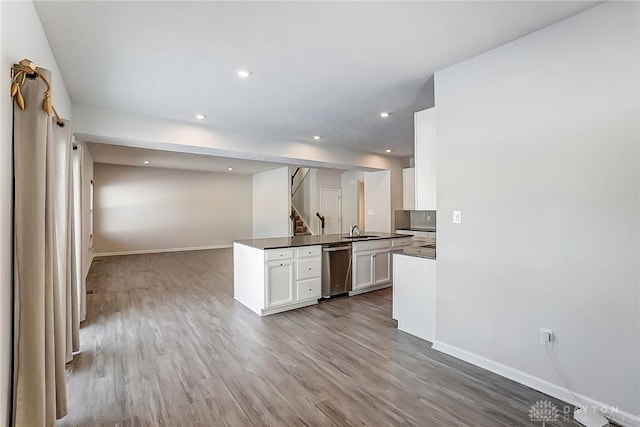 kitchen featuring sink, white cabinets, stainless steel dishwasher, kitchen peninsula, and light wood-type flooring