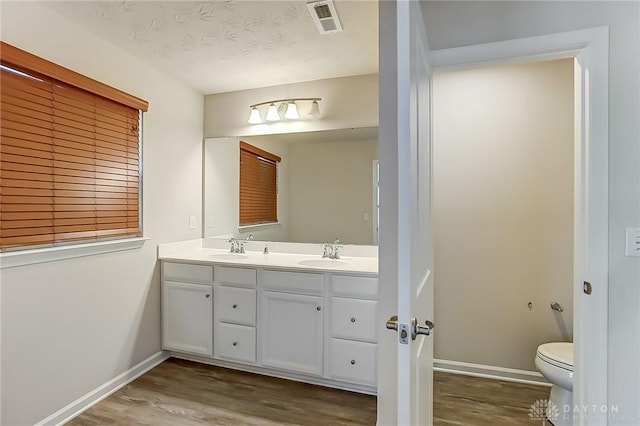 bathroom featuring vanity, a textured ceiling, wood-type flooring, and toilet