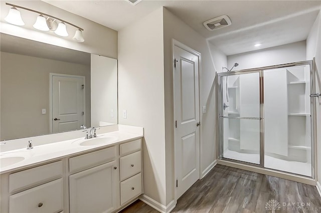 bathroom with vanity, a shower with shower door, and wood-type flooring