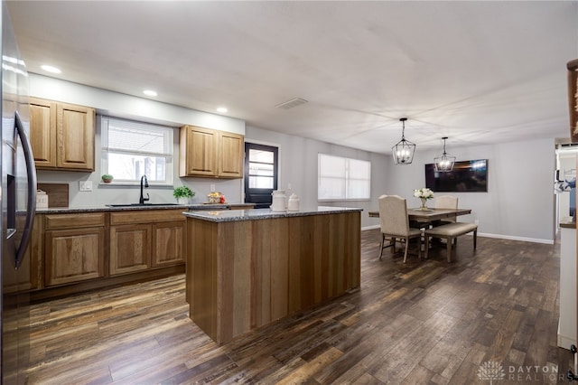 kitchen with sink, stainless steel fridge, hanging light fixtures, dark hardwood / wood-style floors, and a kitchen island