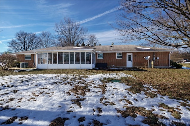 snow covered property featuring cooling unit and a sunroom