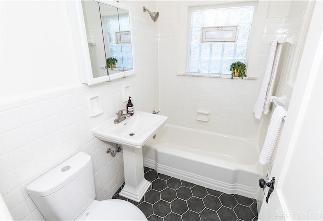 bathroom featuring tiled shower / bath combo, tile walls, tile patterned floors, and toilet