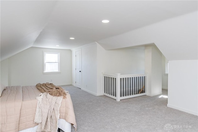 unfurnished bedroom with vaulted ceiling and light carpet