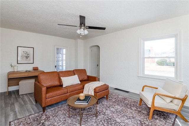 living room with ceiling fan, hardwood / wood-style floors, and a textured ceiling