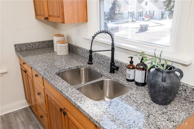 kitchen featuring light stone countertops, sink, and hardwood / wood-style floors