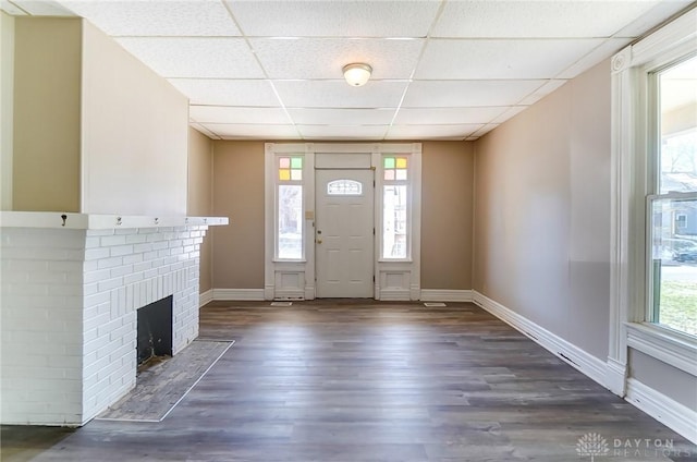 foyer featuring dark wood-type flooring, a fireplace, a paneled ceiling, and baseboards