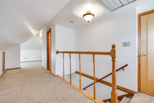 corridor with vaulted ceiling and light colored carpet