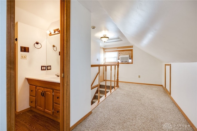 corridor with sink, vaulted ceiling, and carpet