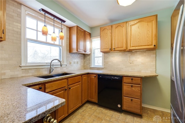 kitchen with sink, stainless steel fridge, black dishwasher, pendant lighting, and light stone countertops