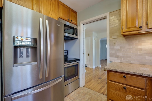 kitchen with light stone counters, appliances with stainless steel finishes, and tasteful backsplash